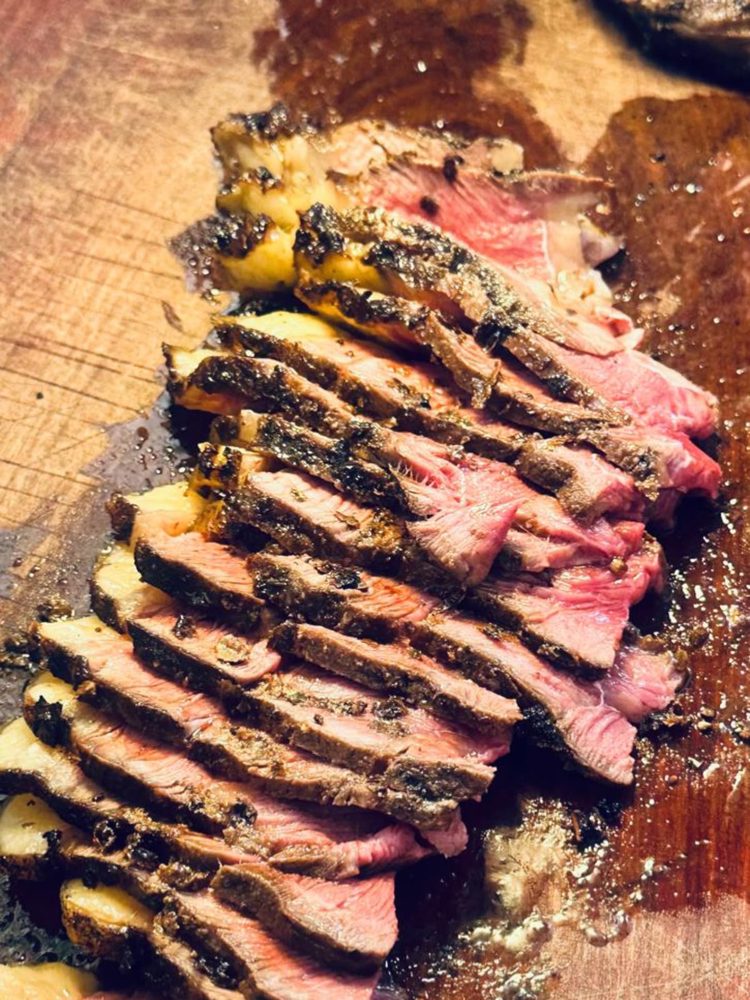 Thick slices of medium-rare steak resting on a wooden board